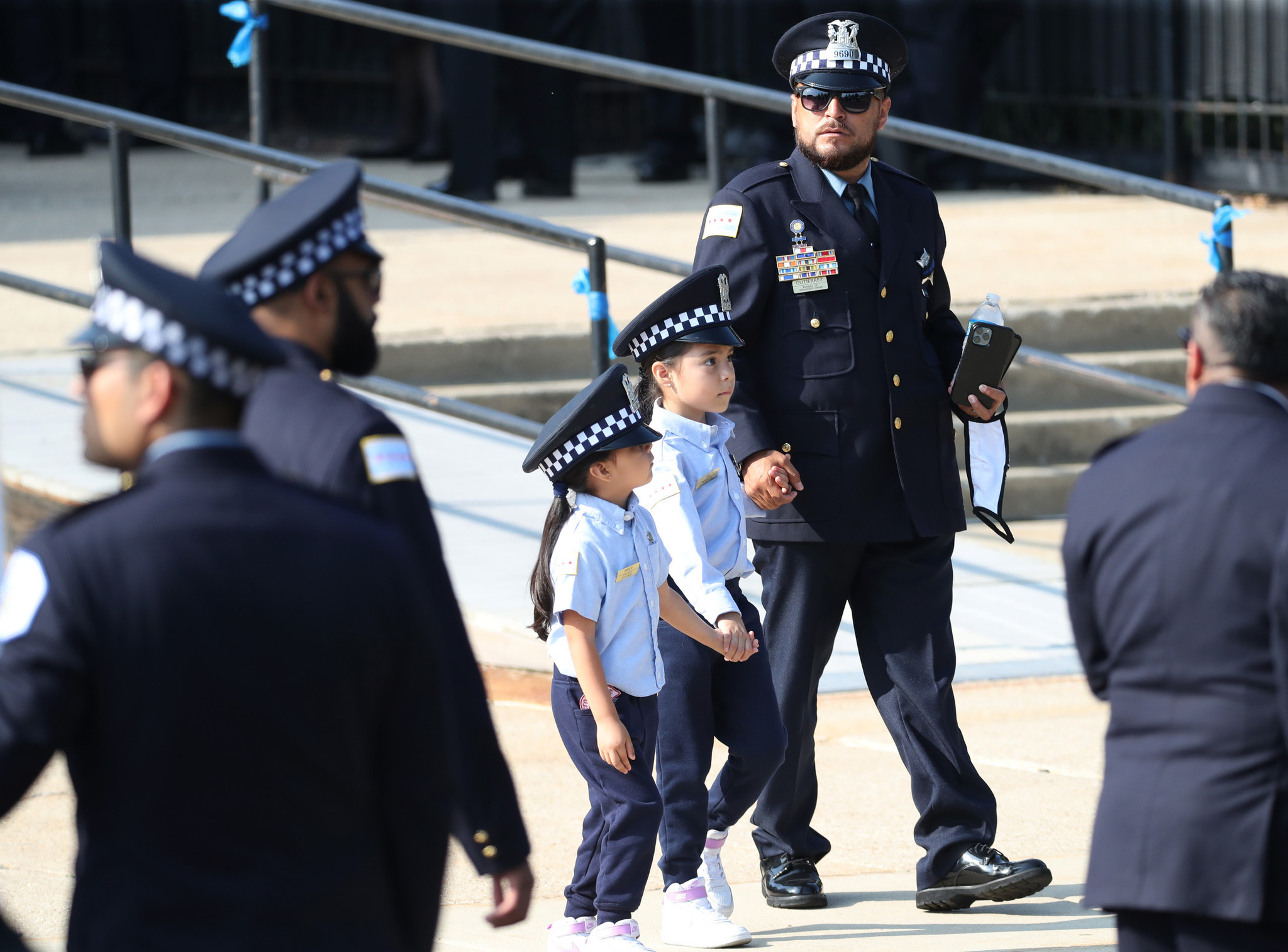 A police officer walks with two girls wearing Chicago Police...
