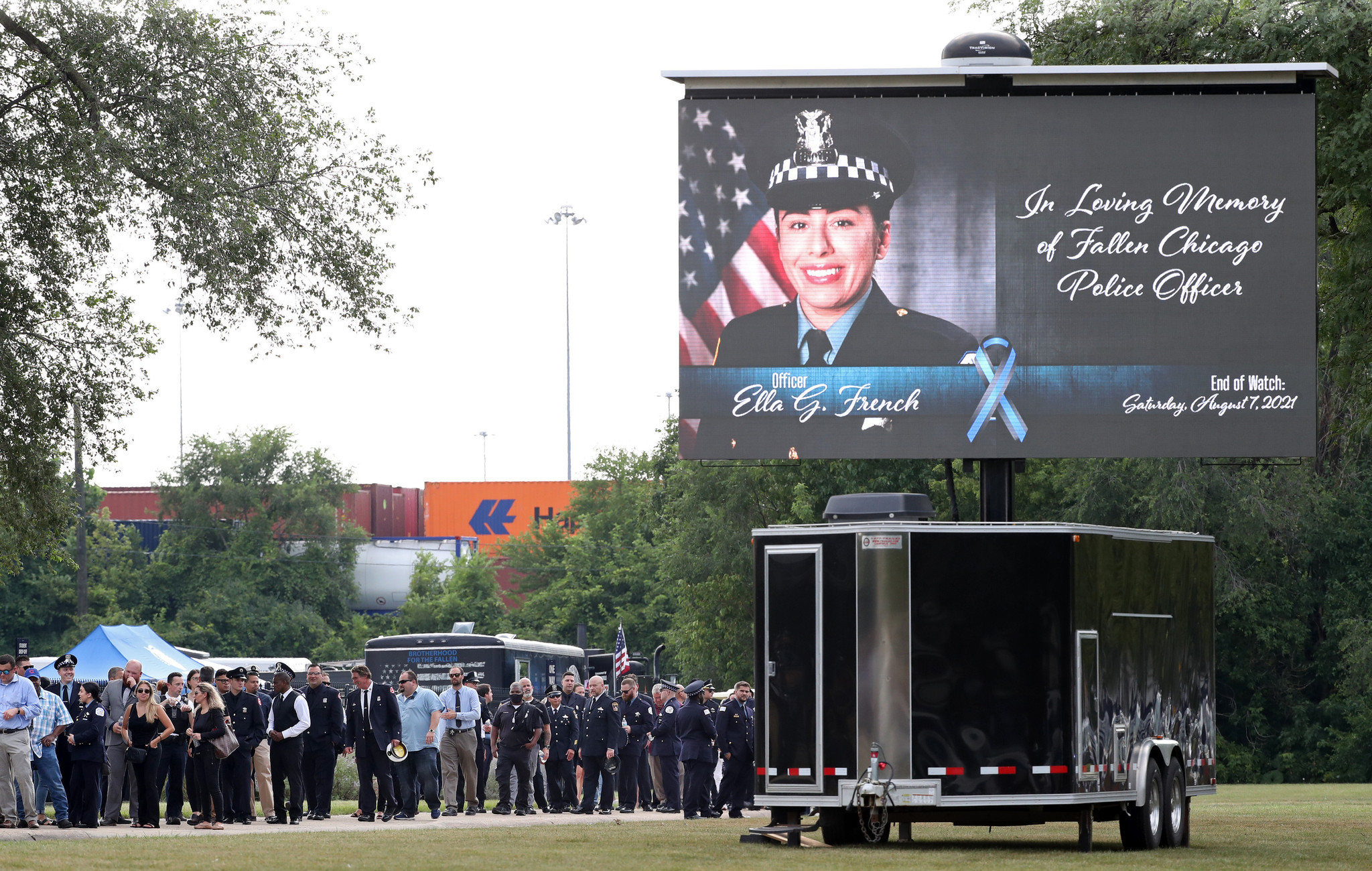 Police officers and other mourners wait in line to attend...