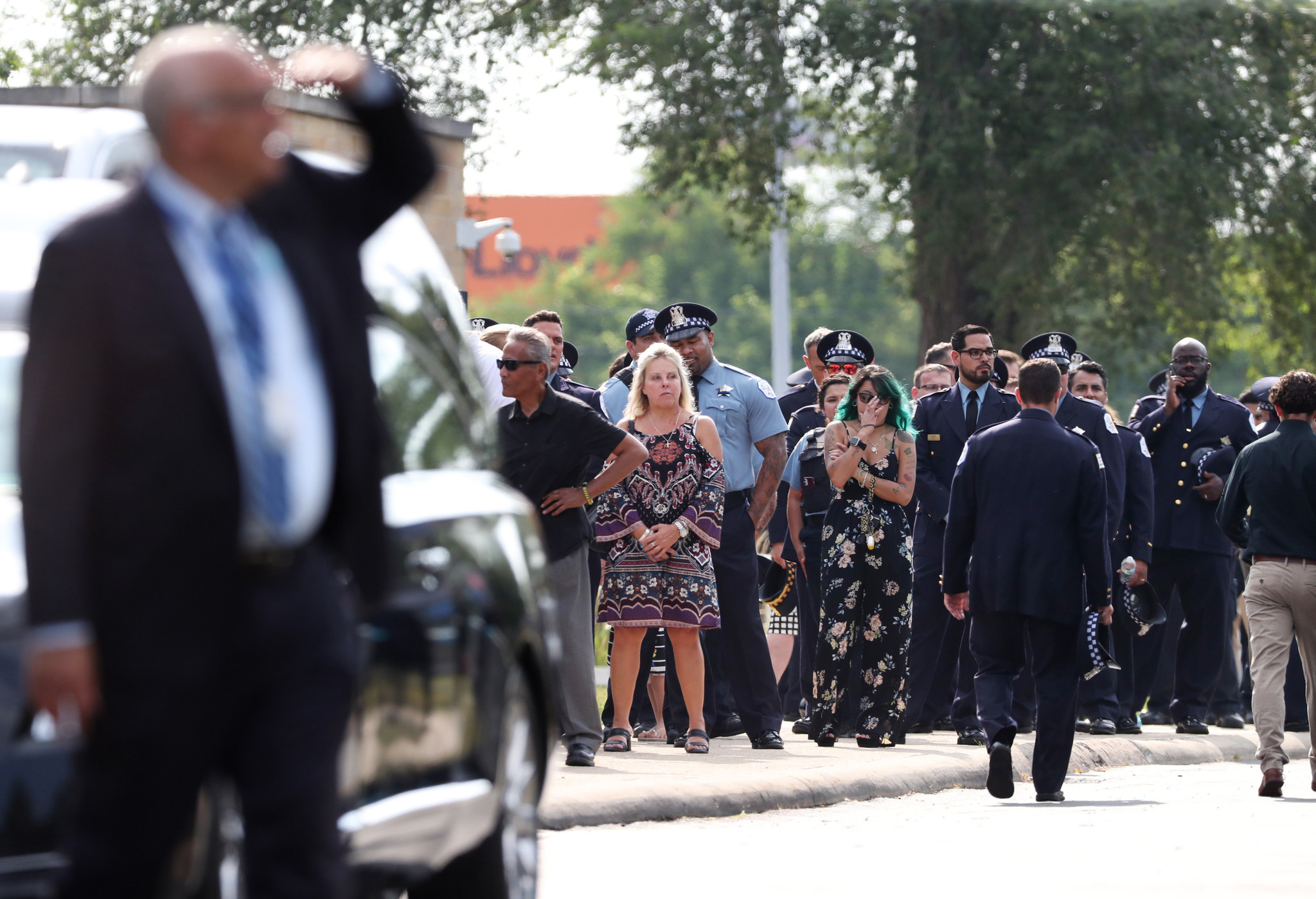 Police officers and other mourners wait in line to attend...