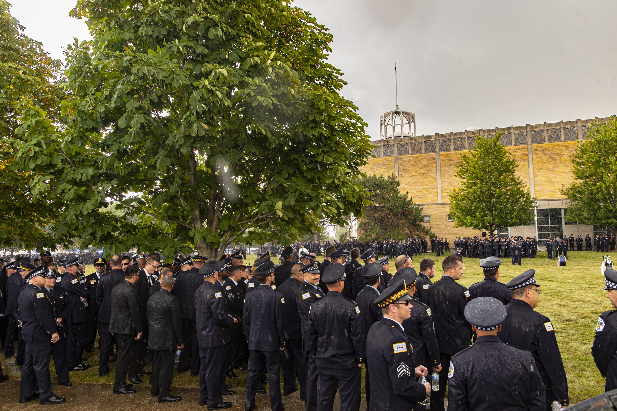Chicago police officers stand in the pouring rain less than...