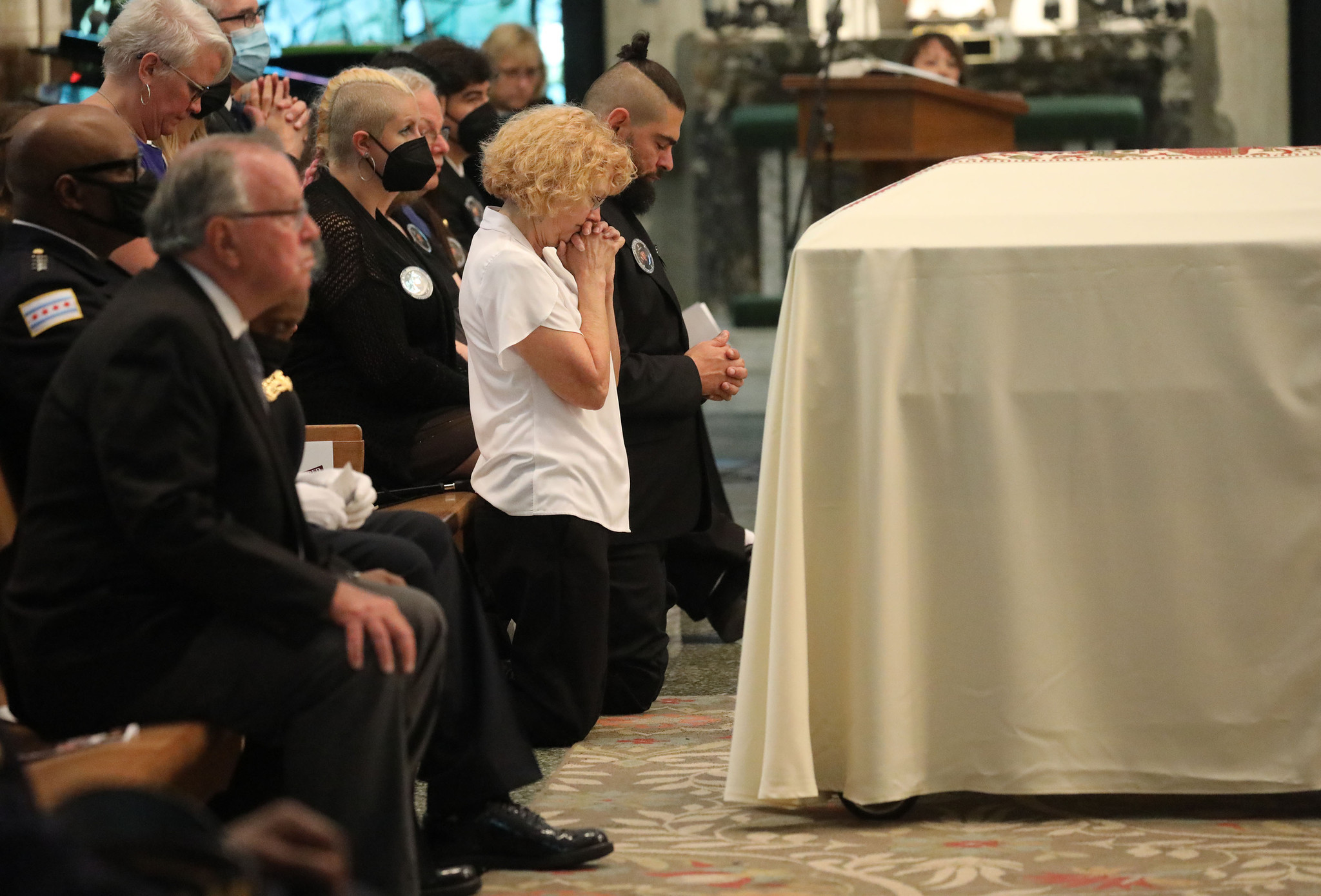 Elizabeth French, in white shirt, prays beside the casket of...