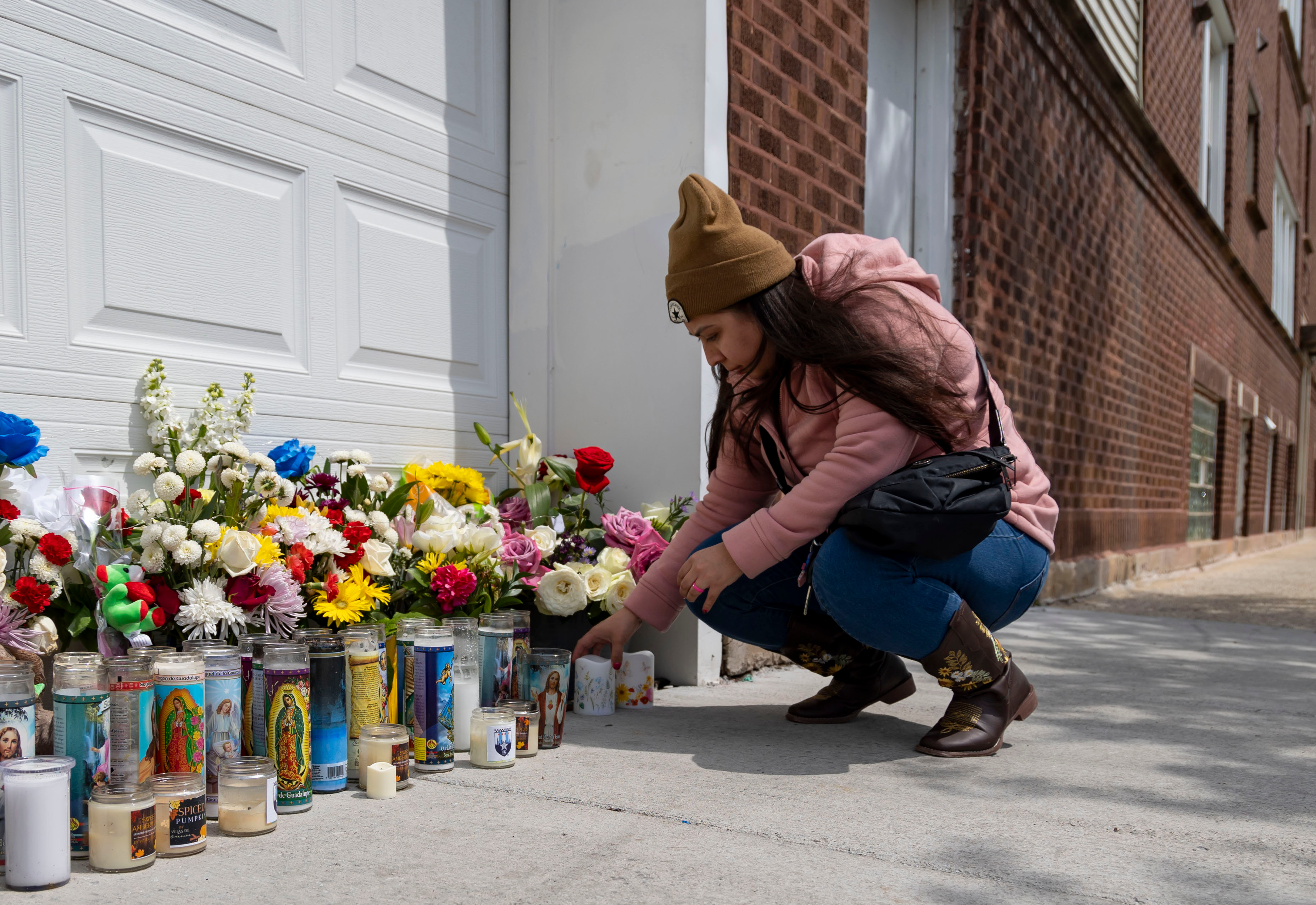 A woman leaves candles, April 28, 2024, at a memorial in Gage Park where Chicago police Officer Luis M. Huesca was shot and killed last weekend. Huesca, a CPD officer for six years, was returning home after a shift in the CPD's Calumet District when he was fatally shot. (Brian Cassella/Chicago Tribune)