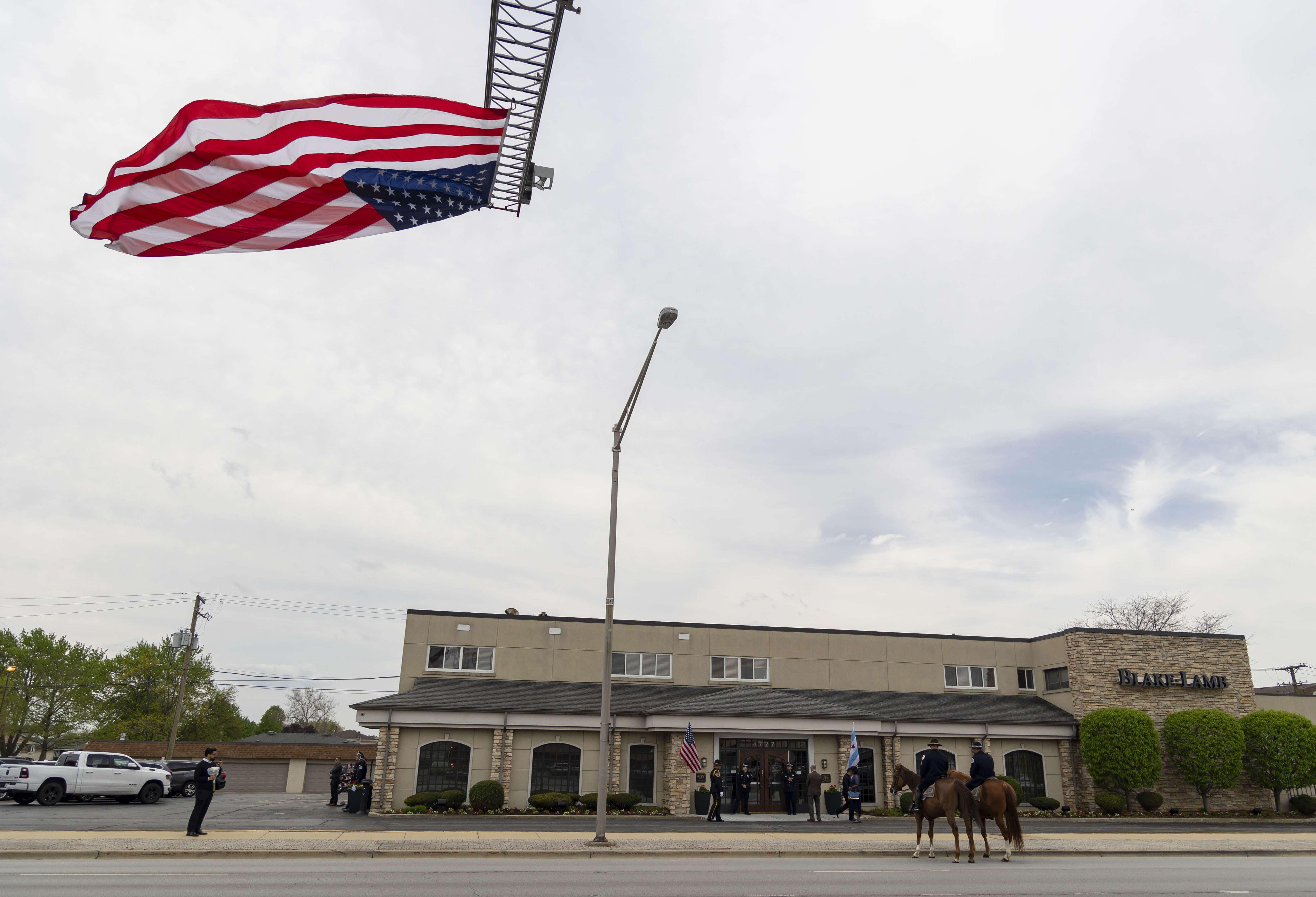 A flag flies from a fire truck ladder during the visitation for Chicago police Officer Luis M. Huesca on April 28, 2024, at Blake-Lamb Funeral Home in Oak Lawn. (Brian Cassella/Chicago Tribune)