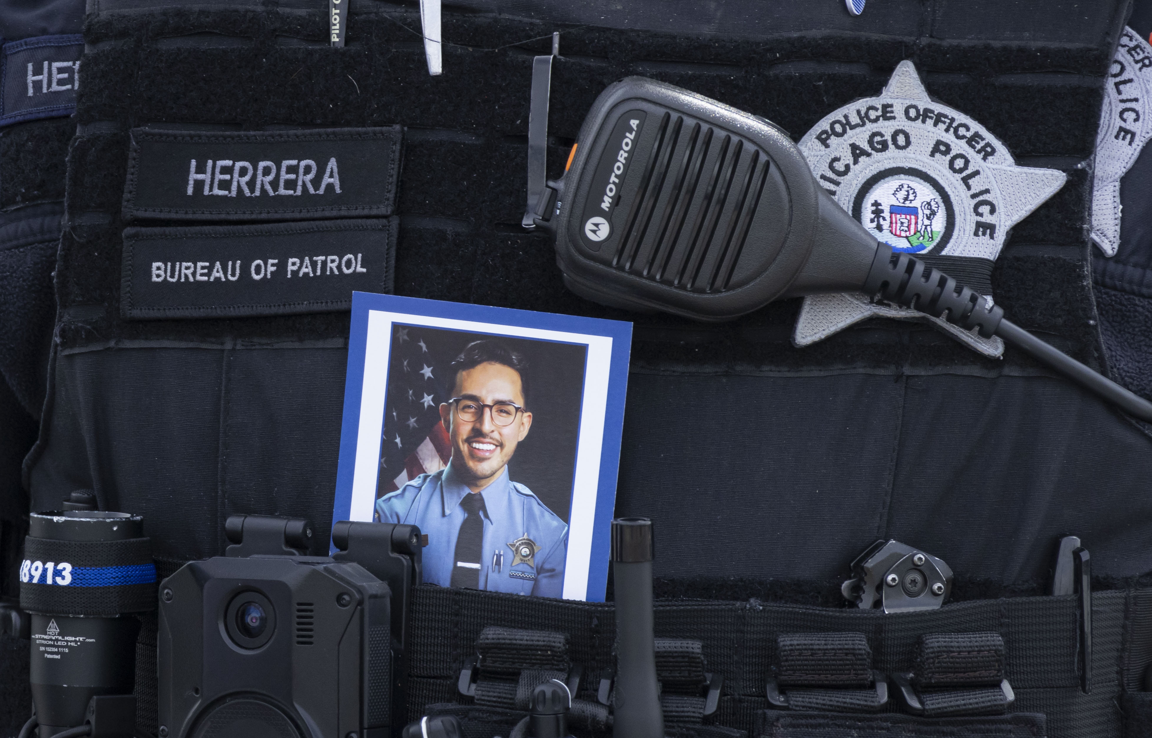 A police officer carries a picture of slain Officer Luis M. Huesca during his visitation on April 28, 2024, at Blake-Lamb Funeral Home in Oak Lawn. (Brian Cassella/Chicago Tribune)