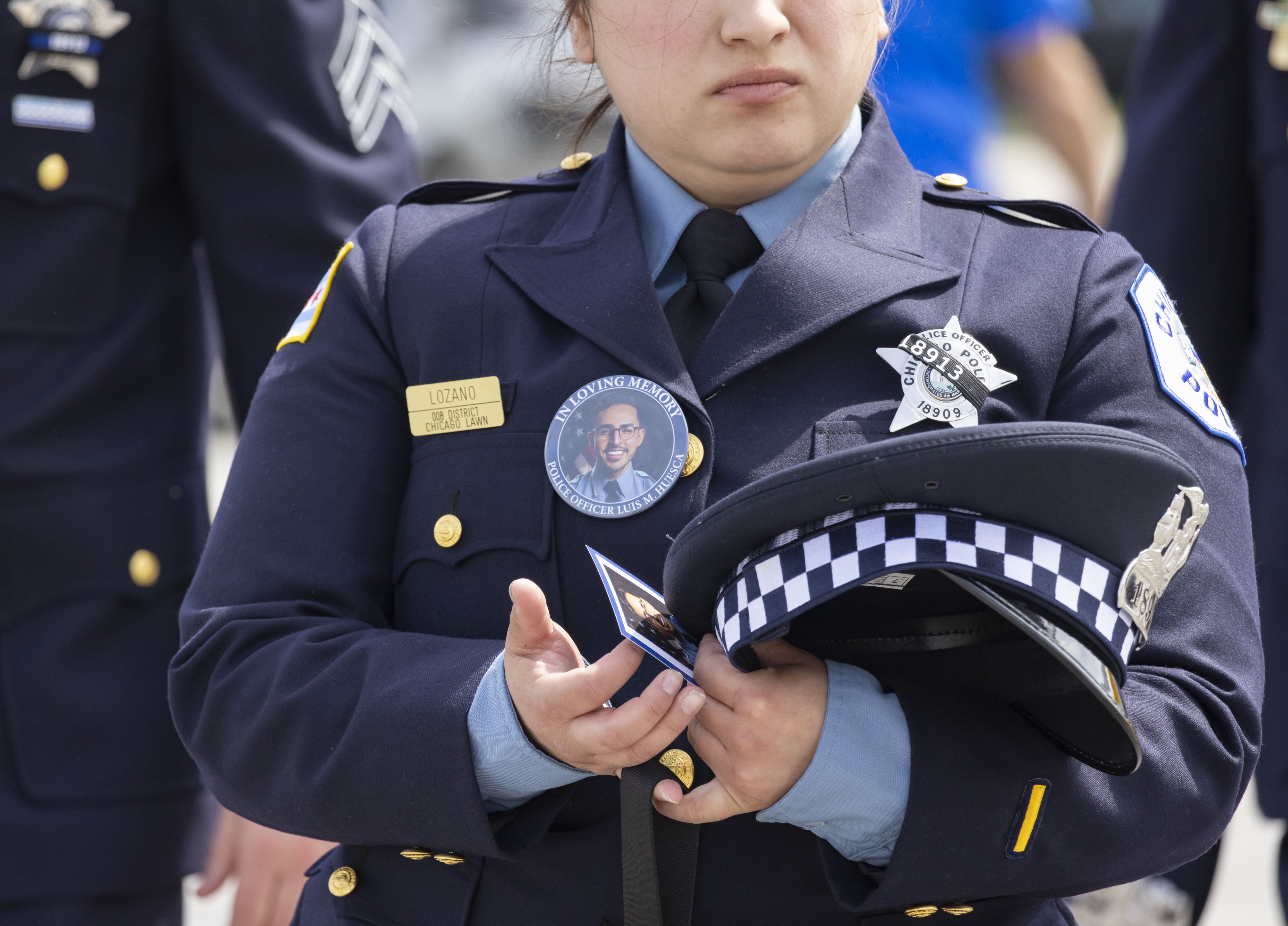 A police officer carries a picture of slain Officer Luis M. Huesca during his visitation Sunday, April 28, 2024, at Blake and Lamb Funeral Home in Oak Lawn. Huesca, a CPD officer for six years, was returning home last week after a shift in the CPD's Calumet District when he was fatally shot. (Brian Cassella/Chicago Tribune)