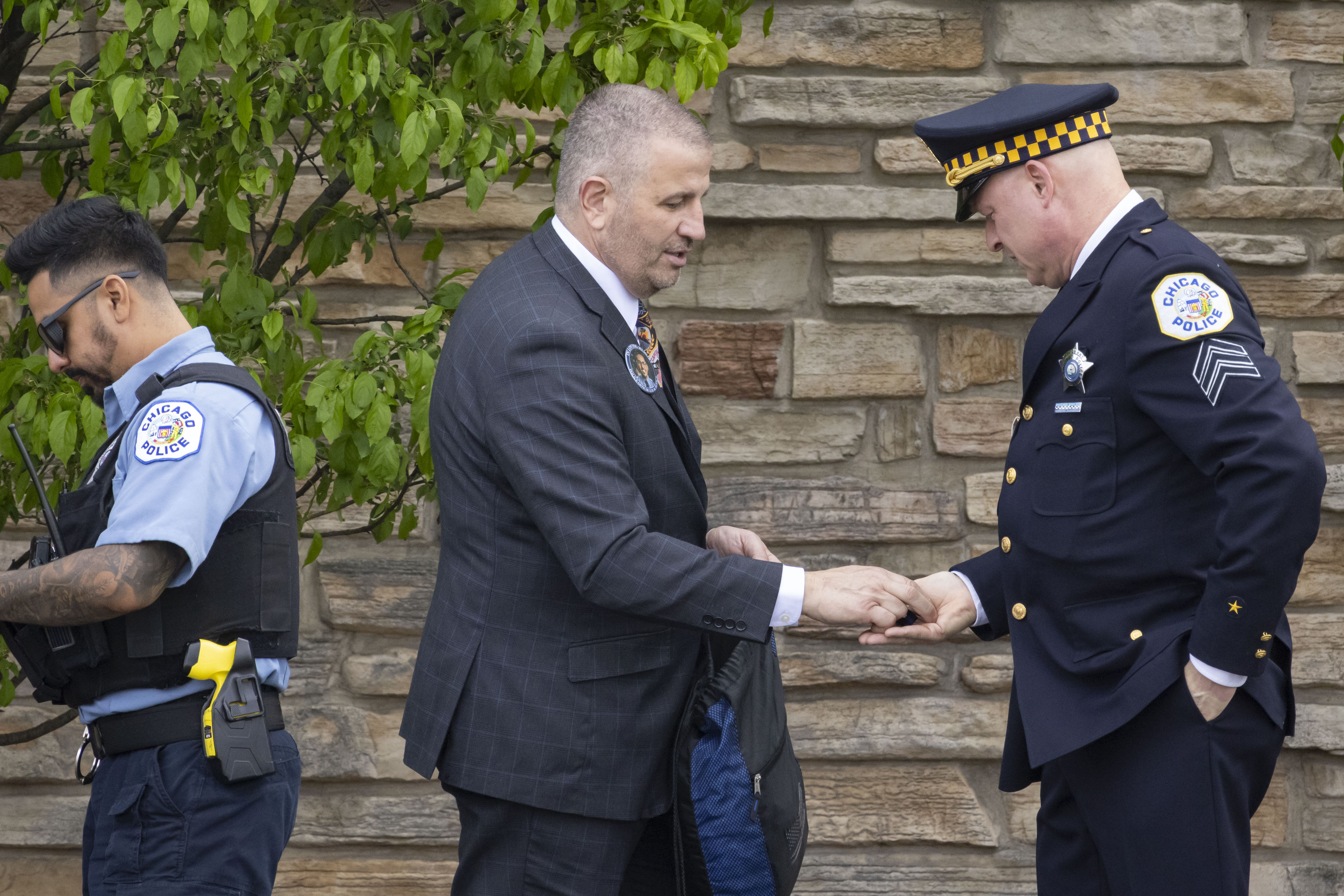 John Catanzara, president of the Chicago Fraternal Order of Police, hands out black bands as officers line up to enter the visitation for Chicago police Officer Luis M. Huesca on April 28, 2024, at Blake and Lamb Funeral Home in Oak Lawn. (Brian Cassella/Chicago Tribune)