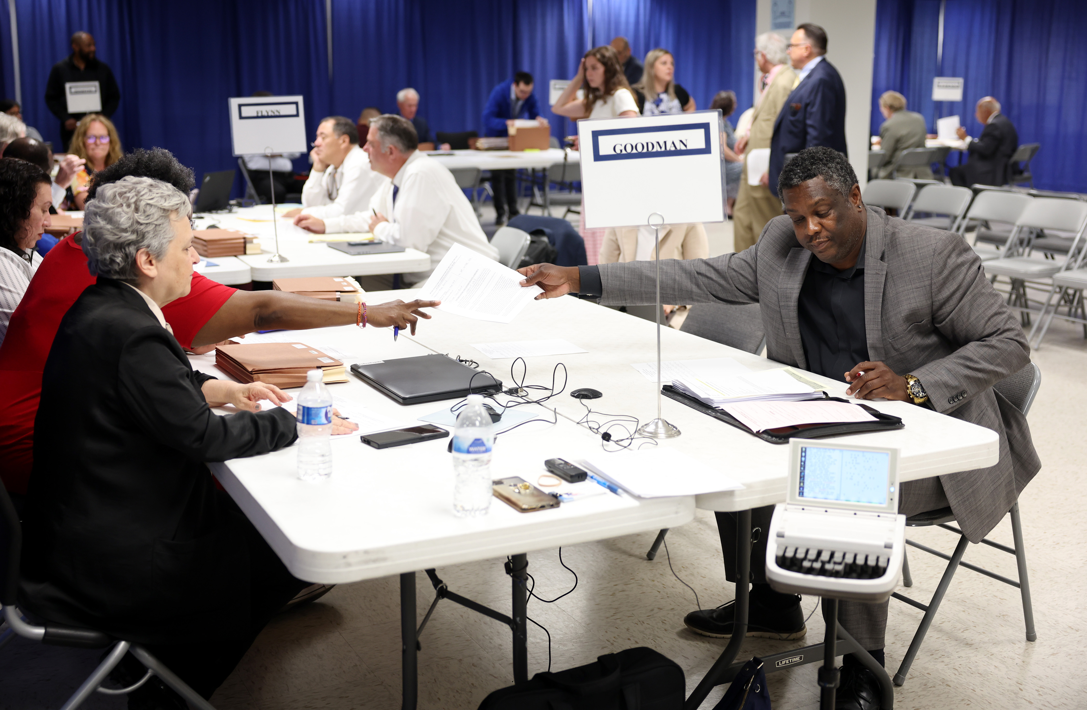 Nathaniel "Nate" Ward, school board candidate for the 10th District, right, hands papers to officials during an initial objections hearing for school board candidates at a Board of Elections meeting room at 69 W. Washington St. on July 9, 2024, in Chicago. (John J. Kim/Chicago Tribune)